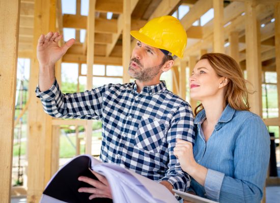 Architect or engineer with blueprints meeting with owner of building house on construction site