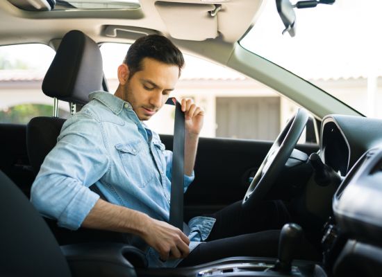 Handsome hispanic man in his 30s putting on her safety seatbelt before starting the car. Driver preparing to start working on a ride share app