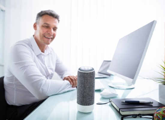 Smiling Mature Man Listening To Music On Wireless Speaker