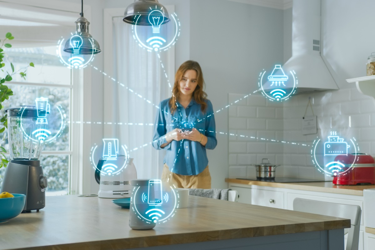 Internet of Things Concept: Young Woman Using Smartphone in Kitchen. She controls her Kitchen Appliances with IOT. Graphics Showing Digitalization Visualization of Connected Home Electronics Devices