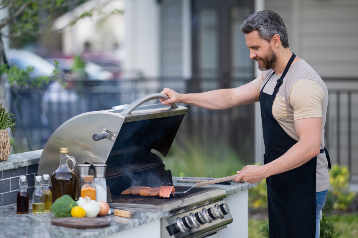 Barbecue concept. Middle aged hispanic man in apron for barbecue. Roasting and grilling food. Roasting meat outdoors. Barbecue and grill. Cooking meat in backyard.