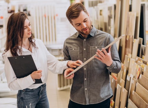 Young man with sales woman choosing tiles at building market