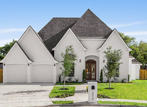 A white house featuring a spacious garage, highlighting the charm of McAllen's real estate options.