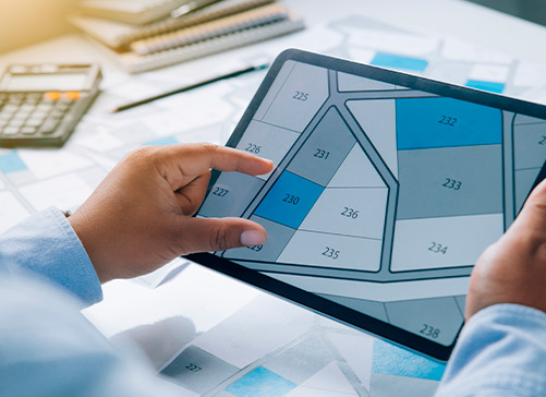 A man views a property map on a tablet, considering whether a custom or pre-built home suits his lifestyle better.