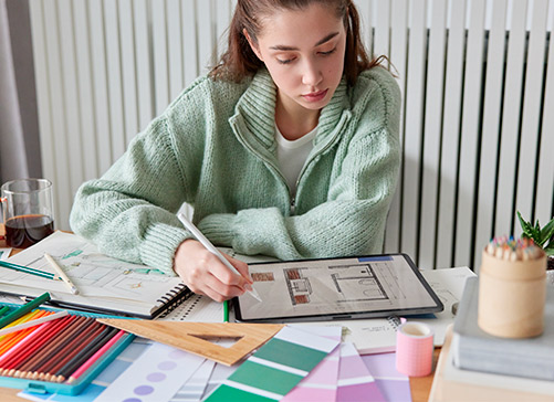 A woman engaged in a design project, exploring the differences between custom and pre-built homes for her lifestyle needs.