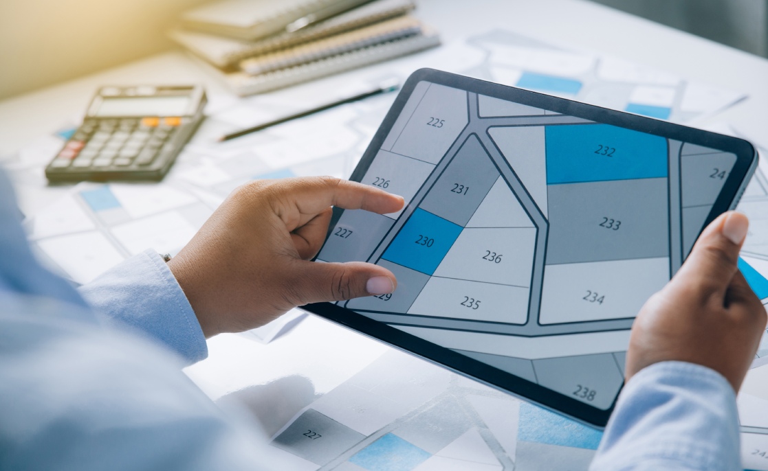 Individual examining a property map on a tablet, discussing key cost factors for custom homes in Brownsville, TX.