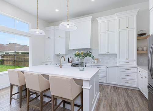 A bright white kitchen featuring a central island with bar stools, showcasing modern design for home remodeling ideas in Texas.
