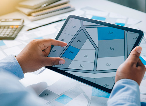 Individual examining a property map on a tablet, discussing key cost factors for custom homes in Brownsville, TX.