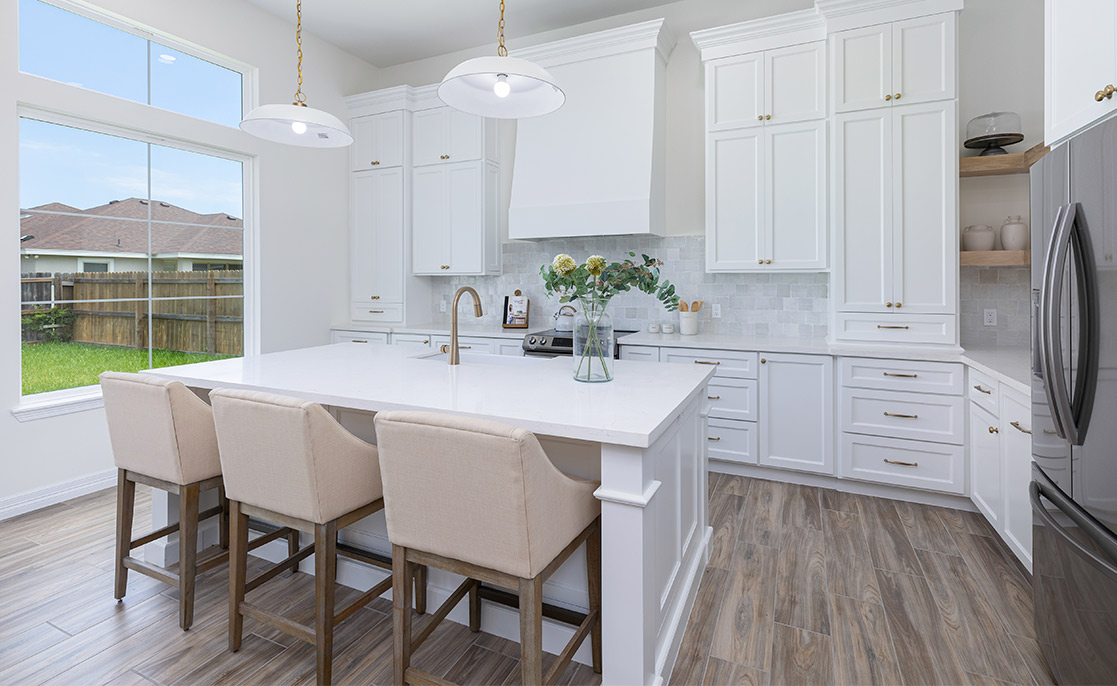 Elegant kitchen with white cabinetry and a central island, highlighting luxury home features and stylish upgrades.