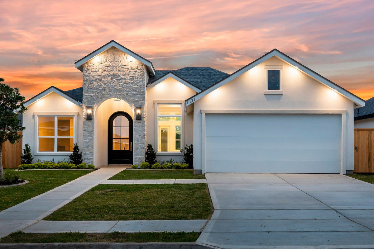 A picturesque home with a driveway and garage at sunset, representing the appeal of custom versus pre-built homes in Harlingen.