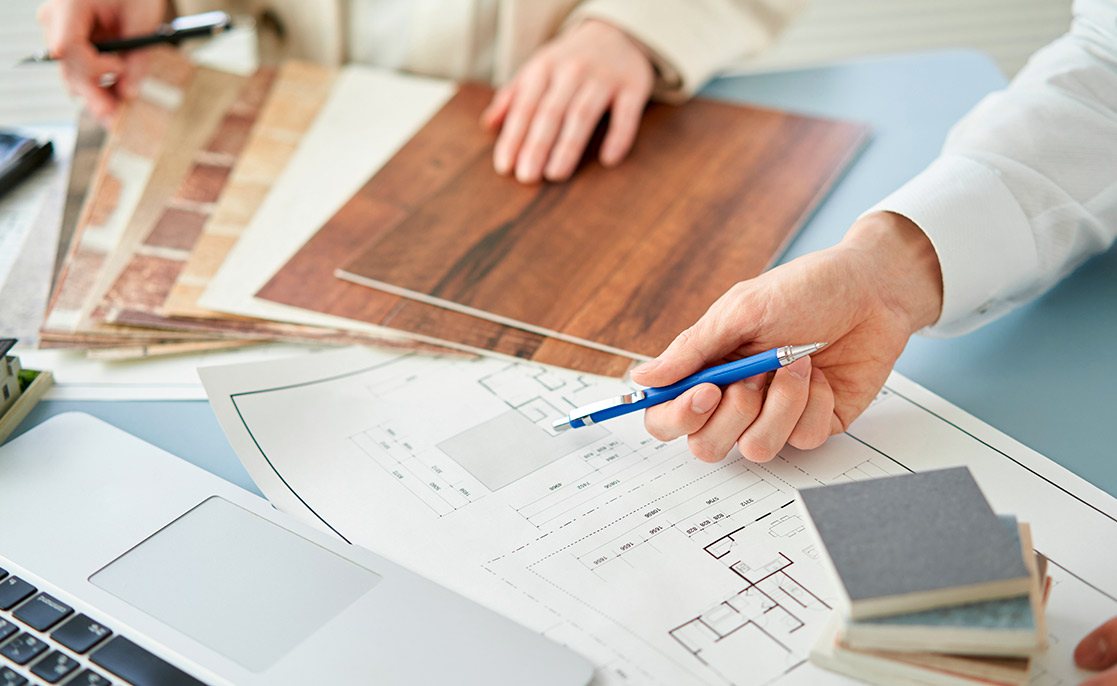 A man uses a laptop and blue pen to evaluate the advantages and disadvantages of custom and pre-built homes in Harlingen, TX.