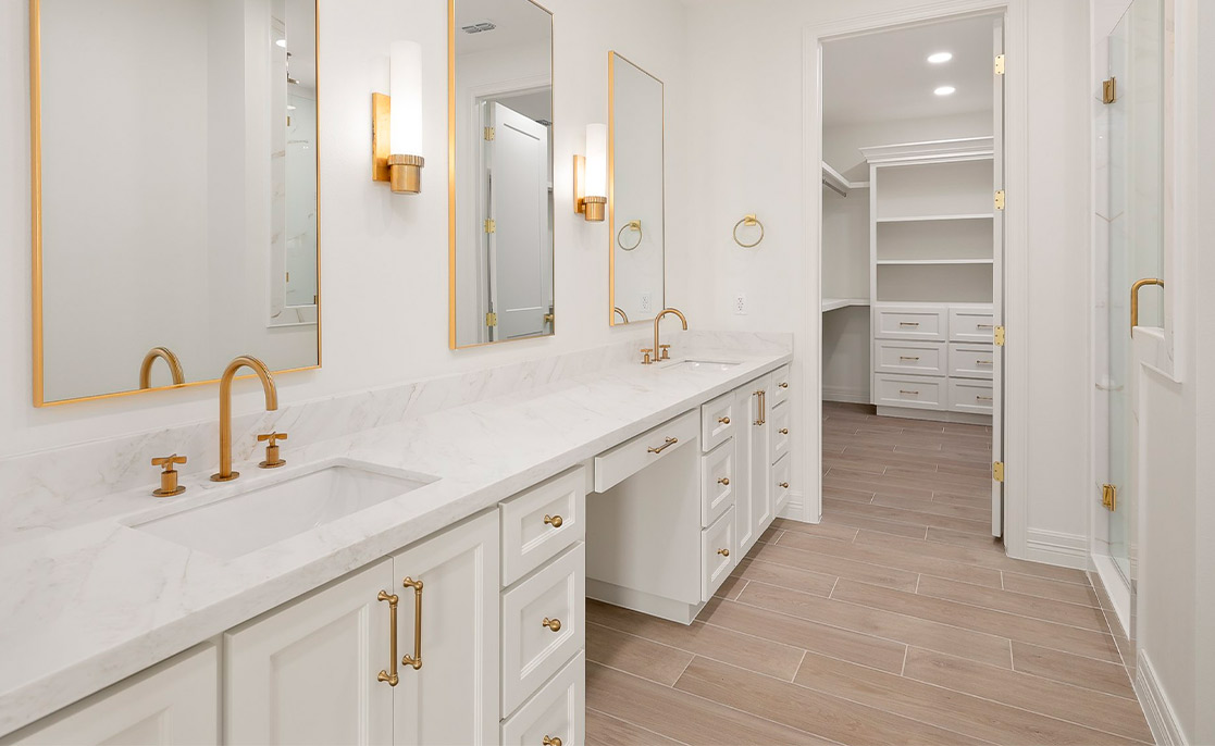 Elegant bathroom with white cabinetry and gold fixtures, showcasing a sophisticated aesthetic for custom home designs.