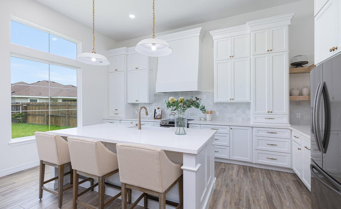 Bright white kitchen with a central island and bar stools, illustrated in the 2026 Rio Grande Valley Home Buyer’s Guide.