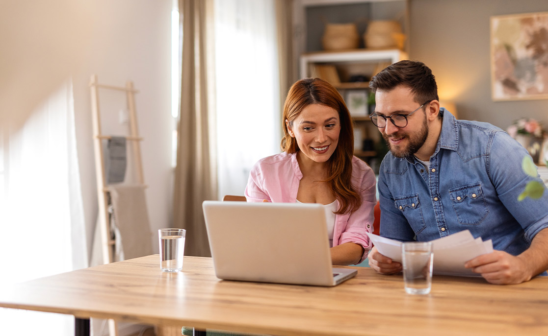 A man and woman are seated at a table with a laptop, discussing the 2026 Rio Grande Valley Home Buyer’s Guide.